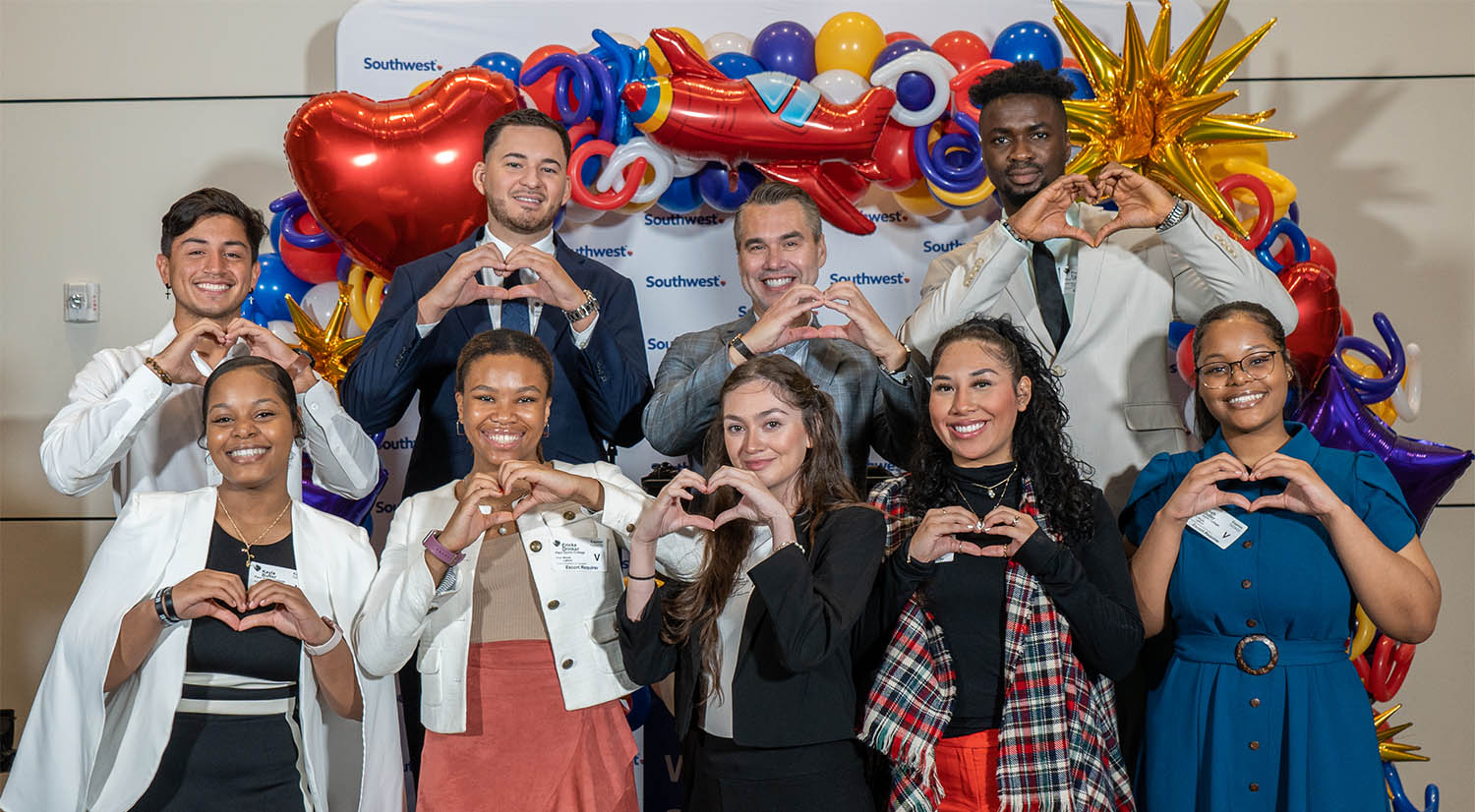 pqc students standing in front of southwest airlines banner making heart symbols with their hands